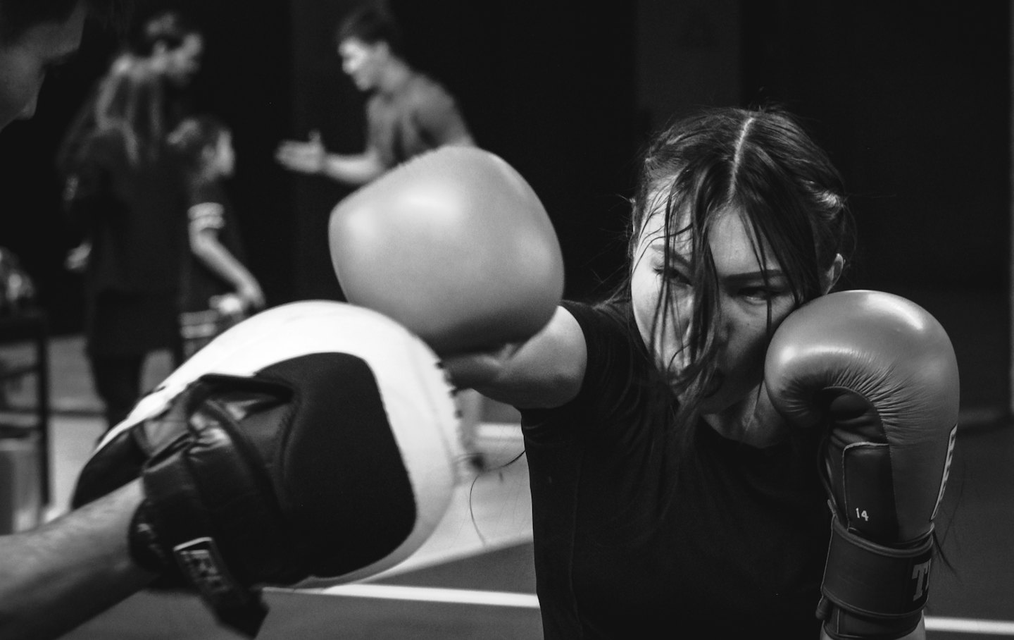 Woman training with boxing focus mitts in a gym.